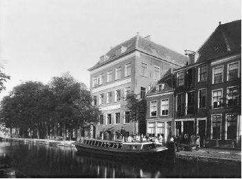 Schwarz-Weiß-Foto mit Blick auf ein vierstöckiges Backsteingebäude an einer Gracht mit der Aufschrift „E.J. Brill“ an der Fassade.