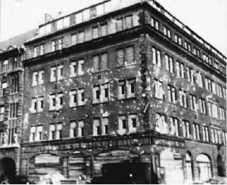 Black and white photograph of the De Gruyter headquarters in Berlin with visible bullet holes all over the building